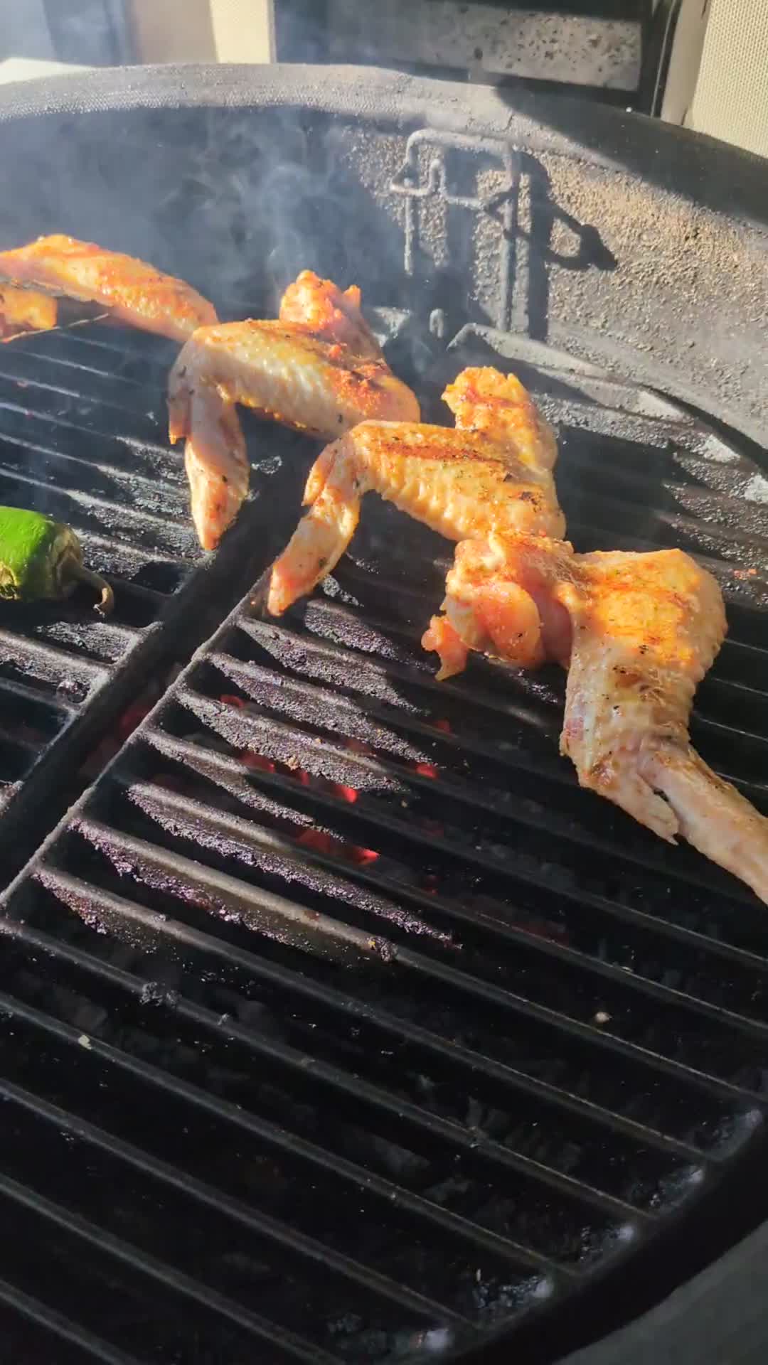 Flipping wings with tongs over hot coals
