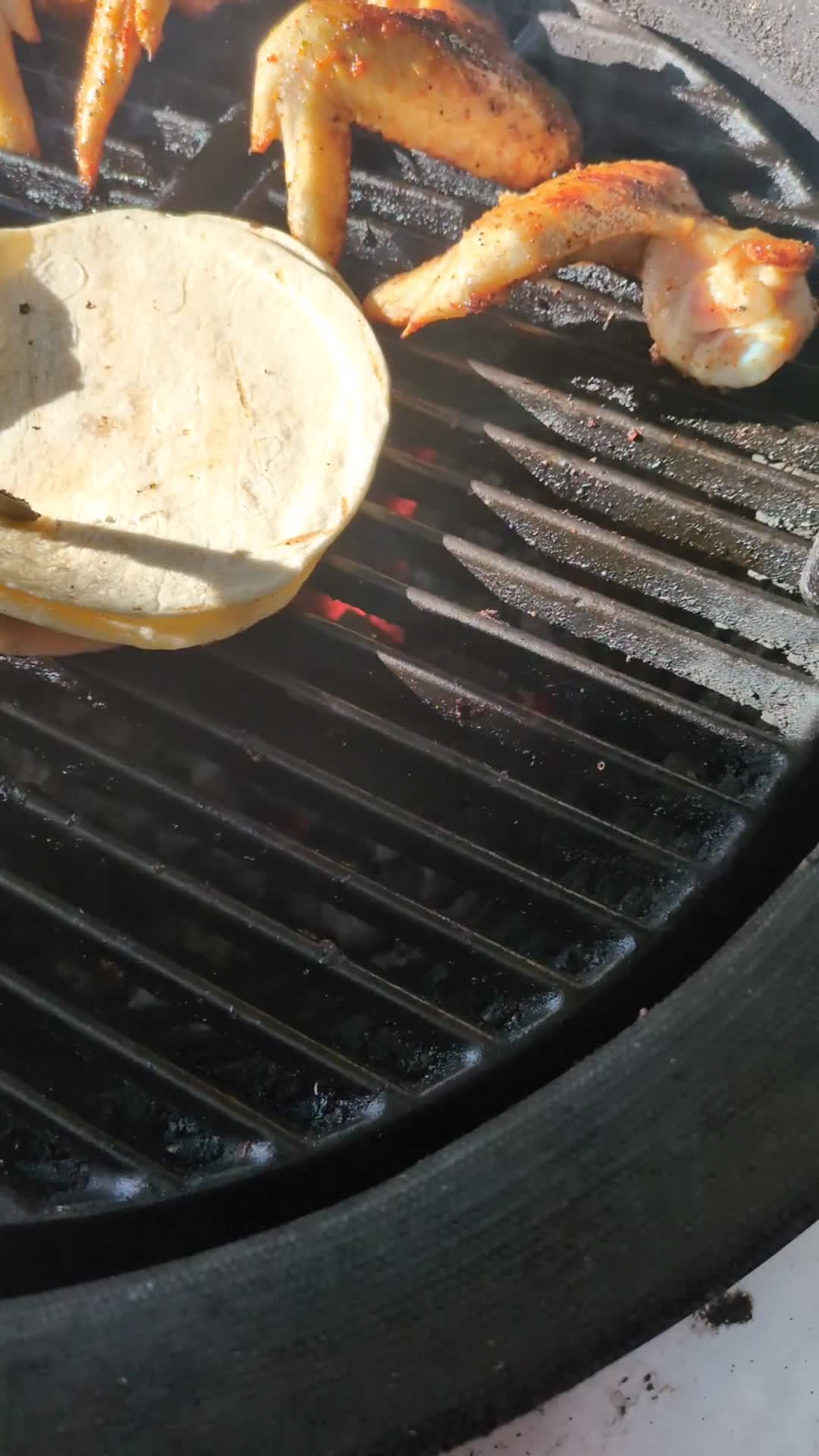 Wings charring next to tortillas on the grill